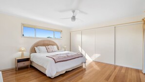 A bedroom with a bed, nightstands, a ceiling fan, a window, and a wardrobe. - Family Tides (Apollo Bay)