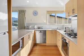 Een moderne keuken met roestvrijstalen apparatuur, houten kastjes en uitzicht op de omgeving.