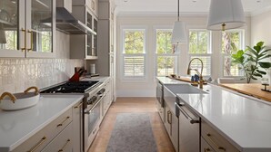 A modern kitchen with white cabinetry, a gas stove, and a large window.