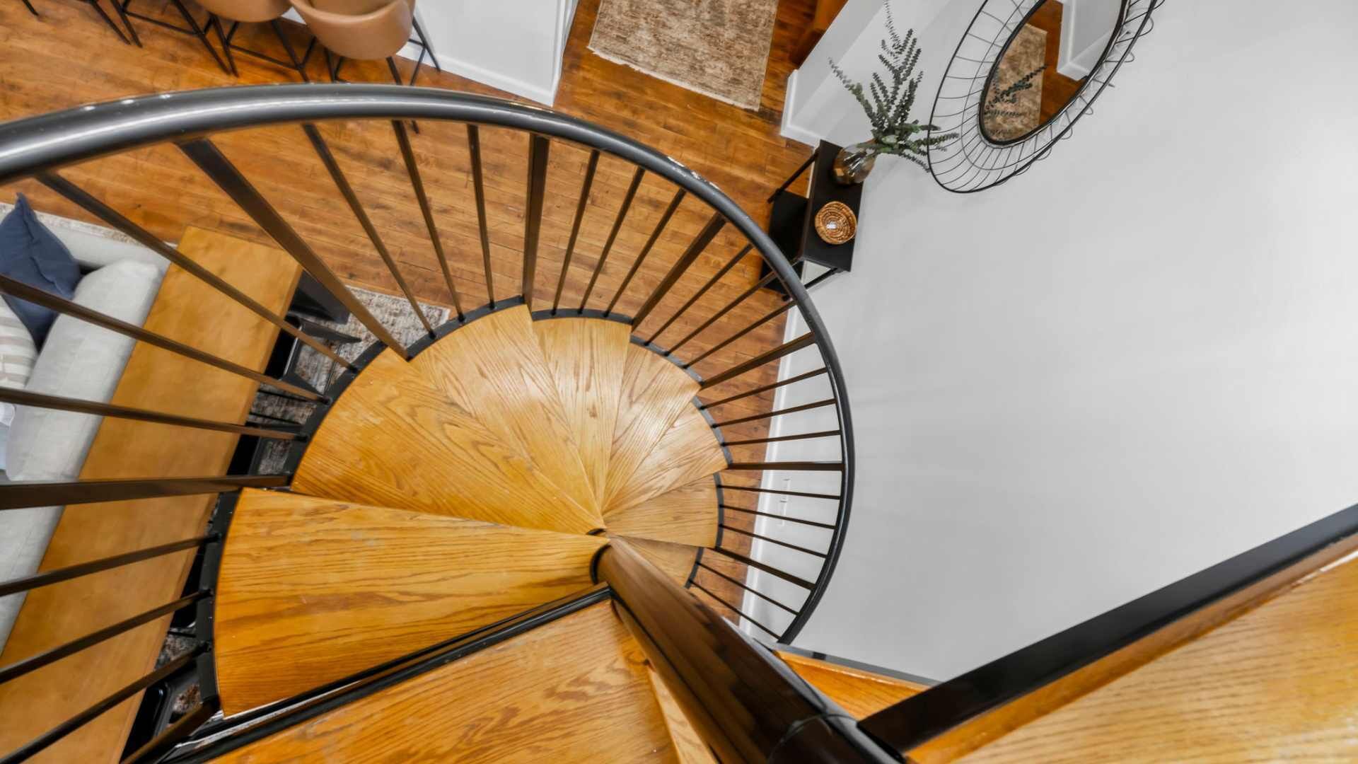Un escalier en colimaçon avec des marches en bois et des rampes en métal.