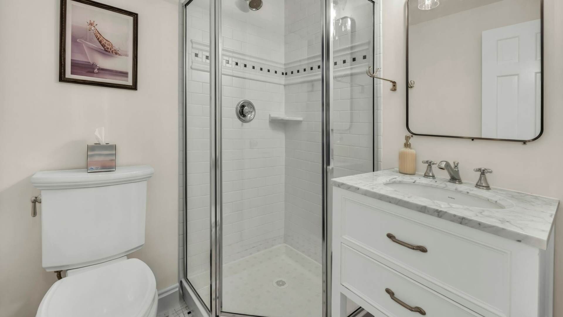 Un bagno con il water, una doccia con sportello in vetro e un mobile lavabo con lavandino e specchio.
