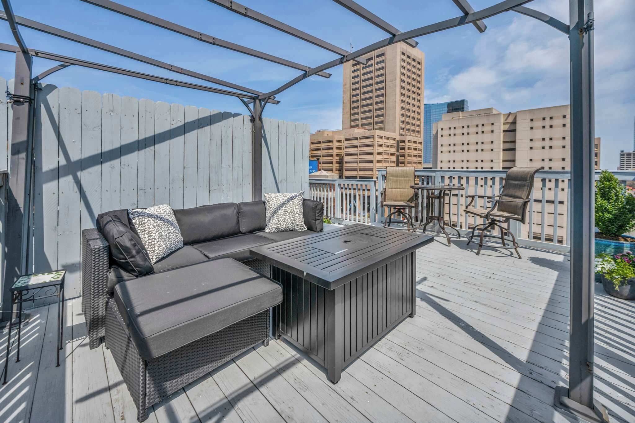A covered outdoor deck with a sofa, a coffee table, and chairs.