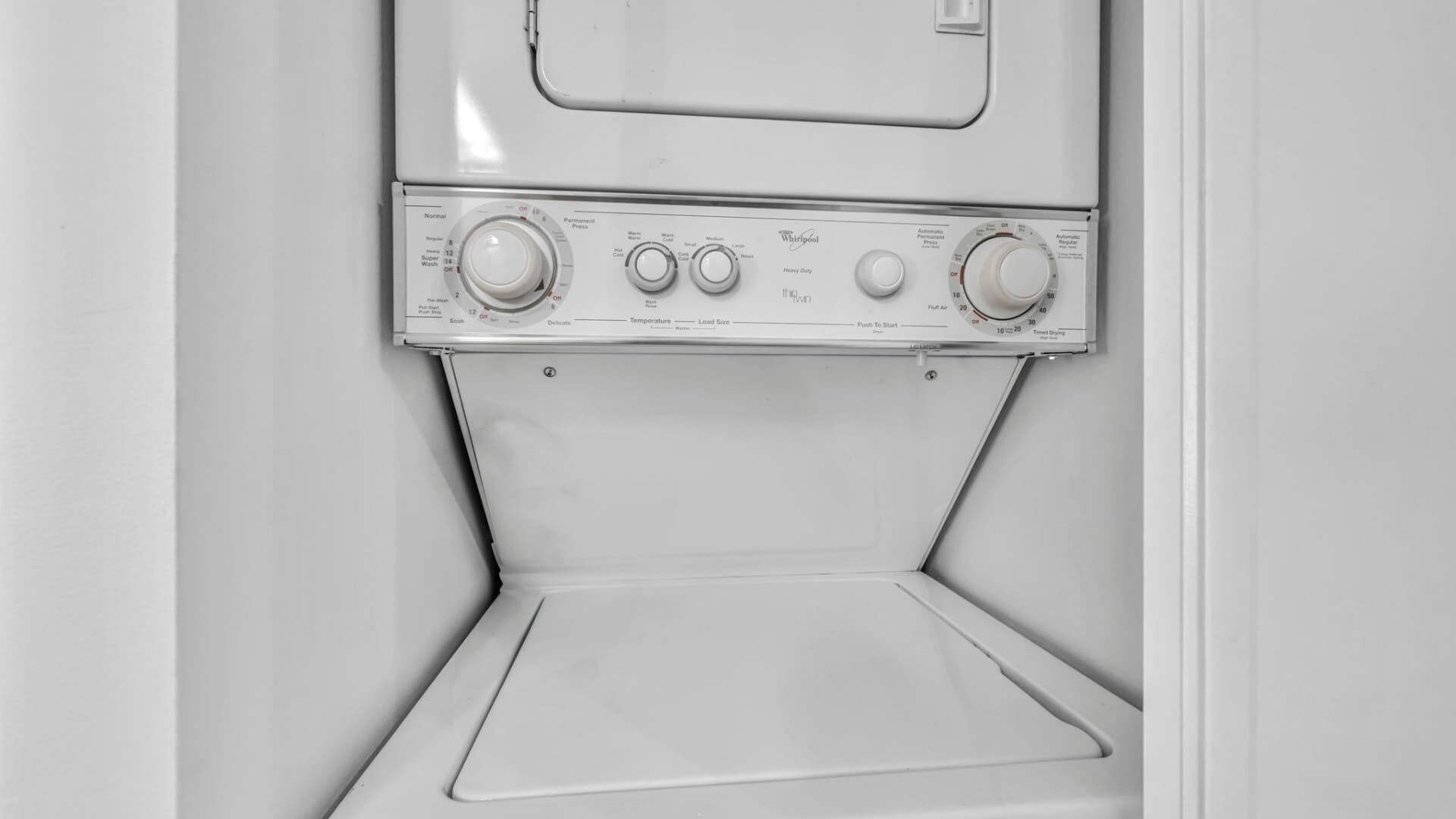 A front view of a Whirlpool washing machine with control knobs for temperature, load size, and spin speed.