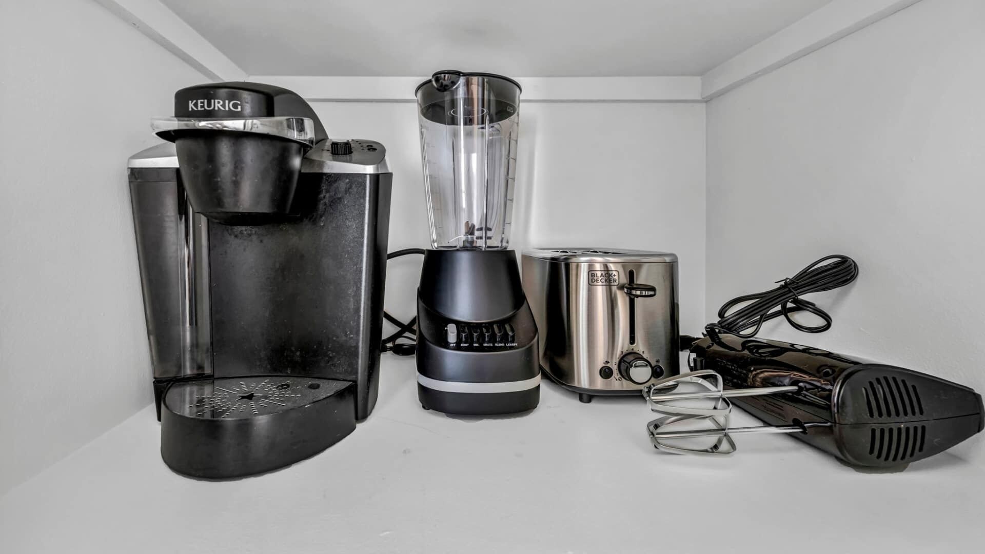 Een keuken met een Keurig koffiezetapparaat, een blender, een broodrooster en een mixer.