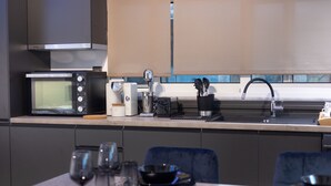 A modern kitchen with a microwave, coffee maker, and sink. - Black suites (Chania)