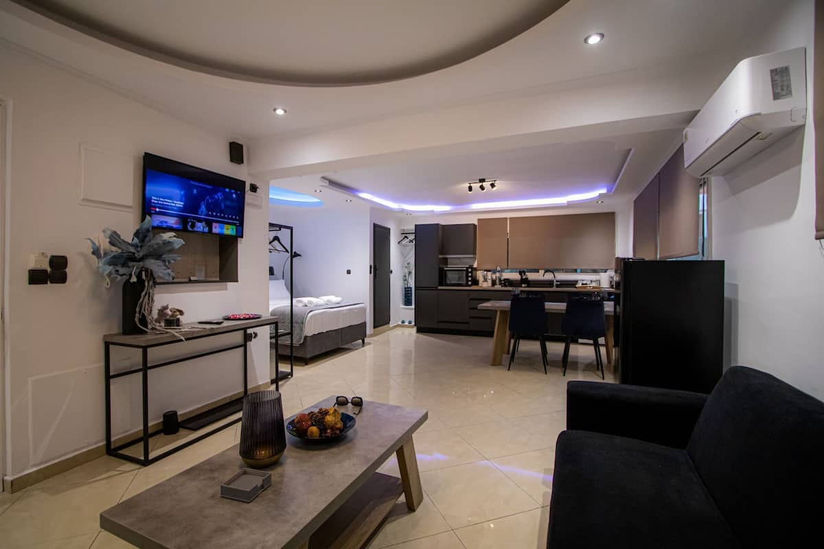 A modern living room with a flat-screen TV, a dining area, and a kitchen.