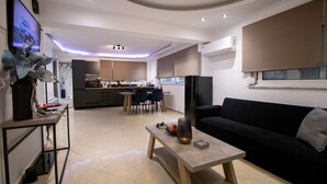 A modern living room with a black sofa, a wooden coffee table, and a TV on the left. - Black suites (Chania)