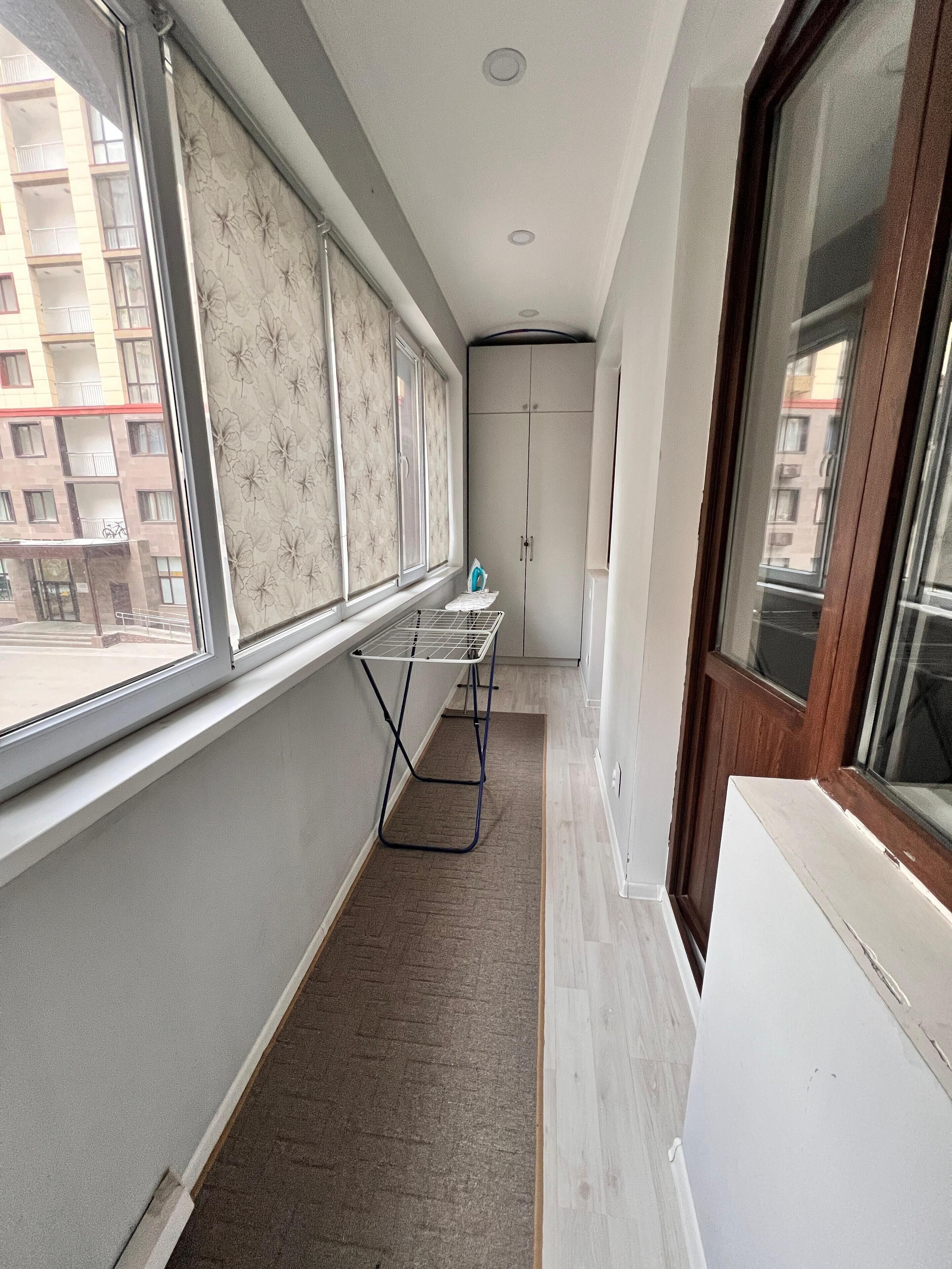 A narrow corridor with a window, a drying rack, and a wardrobe.