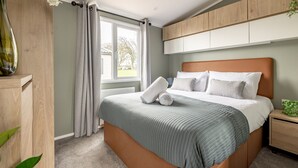Un dormitorio moderno con una cama grande, cabecera de madera y armarios empotrados.