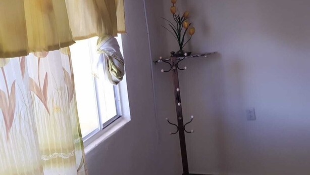 A room with a window, a coat rack, and a flat-screen TV mounted on the wall. - Posada La escondida (San Juan del Rio)