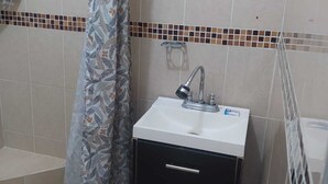A small bathroom with a shower curtain, a sink with a faucet, and a tiled wall. - Posada La escondida (San Juan del Rio)