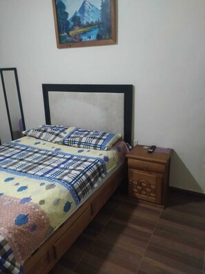 A bedroom with a bed, a nightstand, a painting, and a mirror. - Posada La escondida (San Juan del Rio)
