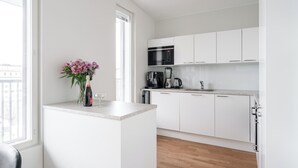A modern kitchen with white cabinets, a built-in microwave, and a coffee maker. - Luxurious 1BR Penthouse with Balcony (Tampere)