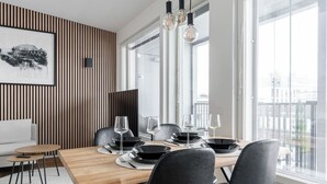 A modern dining area with a wooden table, black chairs, and a city view through large windows. - Luxurious 1BR Penthouse with Balcony (Tampere)