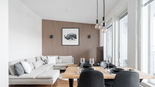 A modern dining area with a wooden table, black chairs, and a white sofa. - Luxurious 1BR Penthouse with Balcony (Tampere)