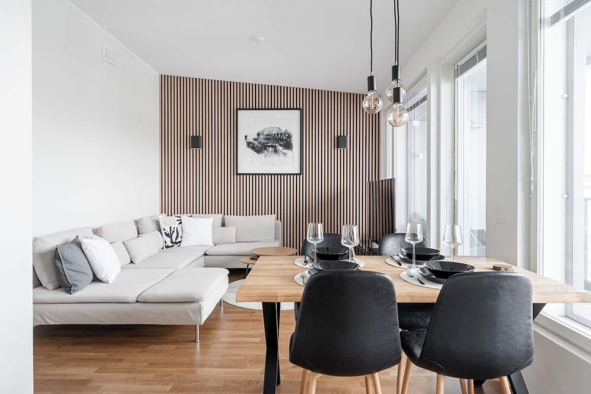 Ein moderner Essbereich mit einem Holztisch, schwarzen Stühlen und einem weißen Sofa.