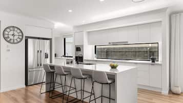 A modern kitchen with a central island, bar stools, a refrigerator, and a large window.