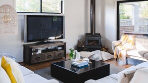 Una sala de estar con televisor, sofá, mesa de centro y estufa de leña.