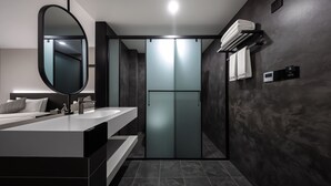 Une salle de bain moderne avec un grand miroir, deux lavabos, un porte-serviettes et une porte en verre dépoli.