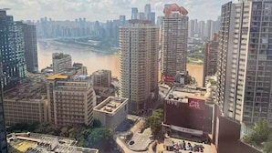 A cityscape with high-rise buildings, a river, and a bridge in the background.