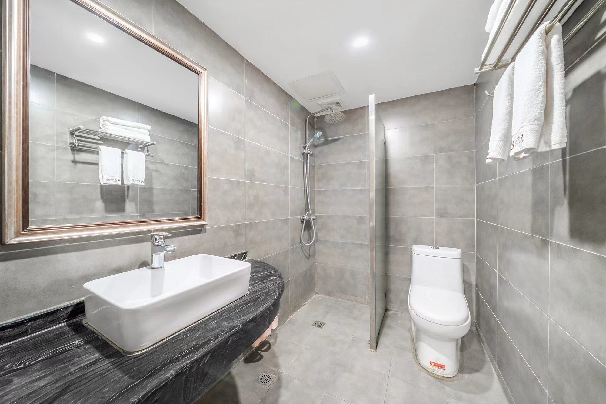 A bathroom with a sink, mirror, shower, and toilet.