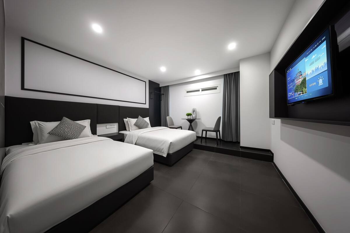 Una habitación de hotel moderna con dos camas, un televisor, una mesita y una silla.