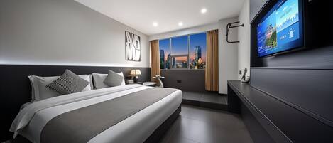 A modern hotel room with a large bed, a flat-screen TV, a city view, and a minimalist design.