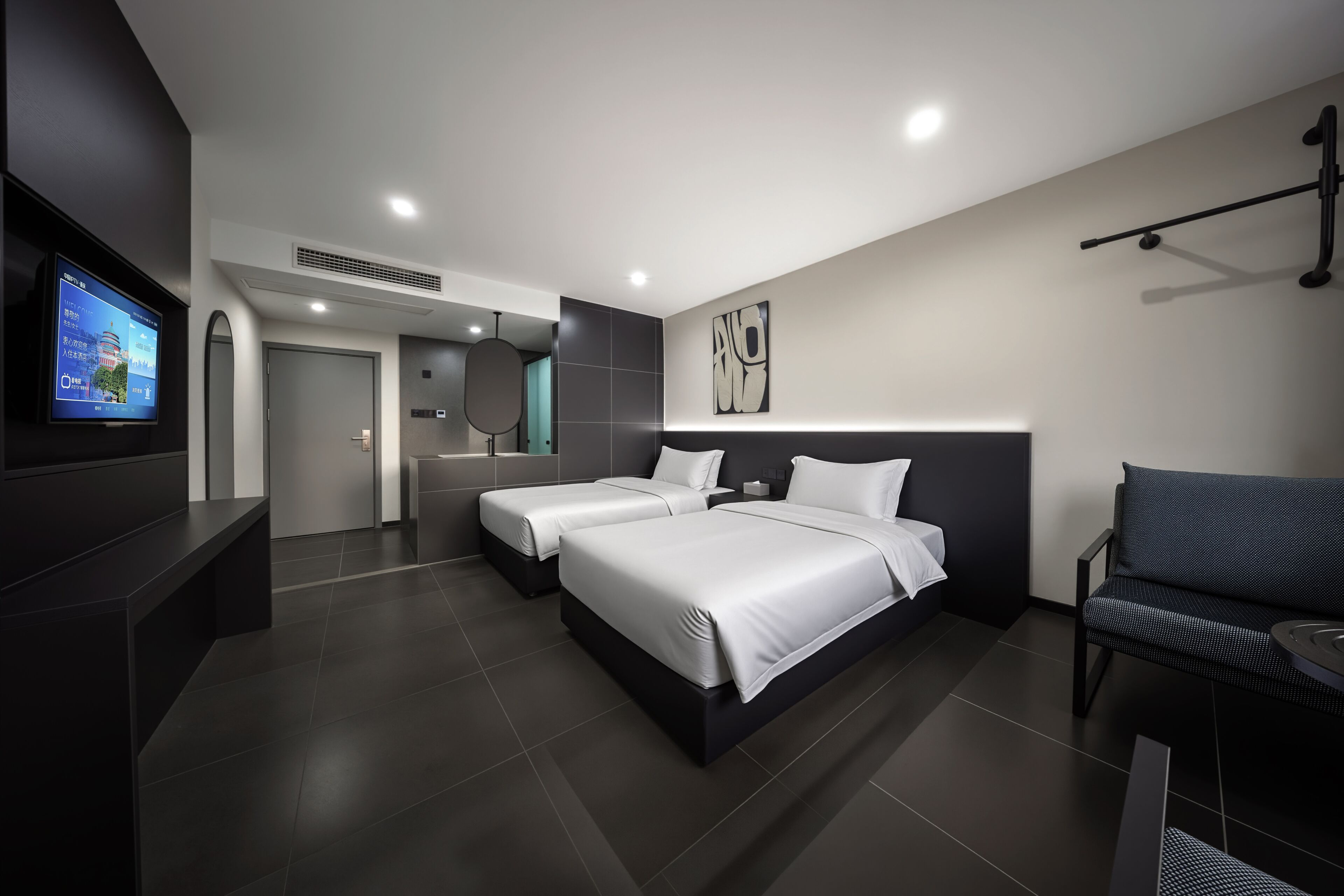 A modern hotel room with two beds, a TV, a sofa, and a wall-mounted artwork.