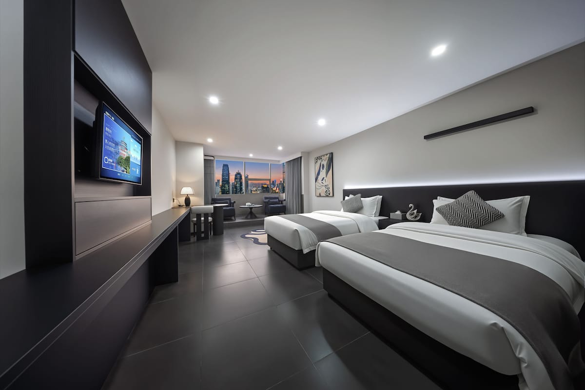Una habitación de hotel moderna con televisión, dos camas, escritorio y vistas a la ciudad.