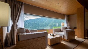 A modern interior with a sofa, armchair, and coffee table, large windows with a mountain view, and wooden ceiling. - The Mountain Route (Guang'an)