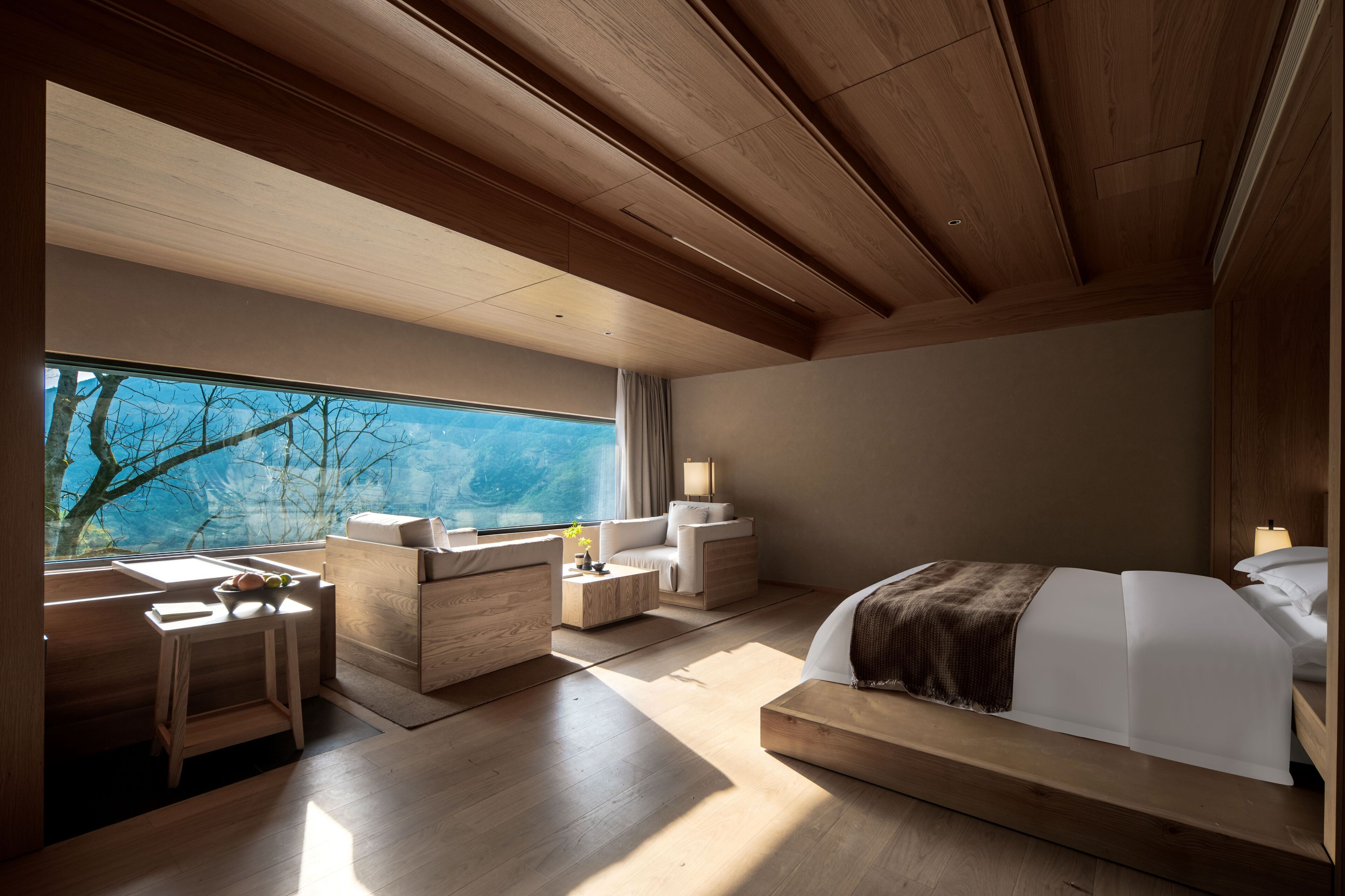 A modern bedroom with a large window, wooden furniture, and a bed with a view of the outdoors.