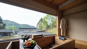 A wooden bench with a bowl of fruit, a towel rack, and a view of a mountain. - The Mountain Route (Guang'an)