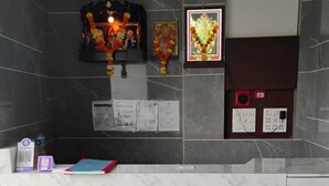 Una recepción con encimera de mármol, un pequeño altar con iconos religiosos y un cuadro eléctrico en la pared.
