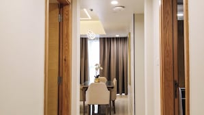 A hallway with wooden doors, a dining area with a table and chairs, and recessed ceiling lights. - Apartment 2BD,Royal Home , Deluxe, Beach View, Abu Dhabi (Abu Dhabi)