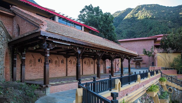 A traditional building with a covered walkway and a stone wall. - Jungle Mahal Wellness Resort (Chandragiri)