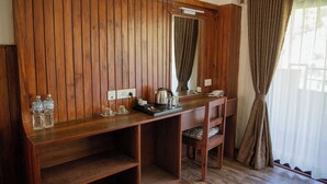 A wooden desk with a kettle, salt and pepper shakers, and two water bottles. - Jungle Mahal Wellness Resort (Chandragiri)