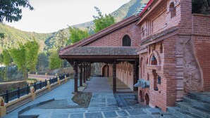 A traditional brick building with a tiled roof, a covered walkway, and stone steps leading to the entrance. - Jungle Mahal Wellness Resort (Chandragiri)