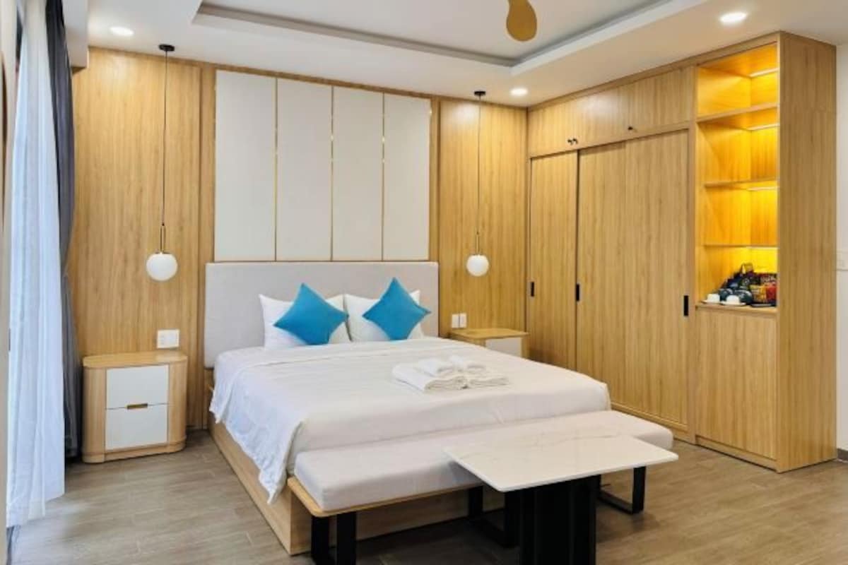 A modern bedroom with a bed, bedside tables, a wardrobe, and a bench.