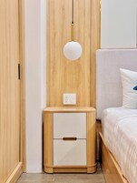 Un dormitorio con un armario de madera, una mesita de noche con lámpara y una cama con almohada.