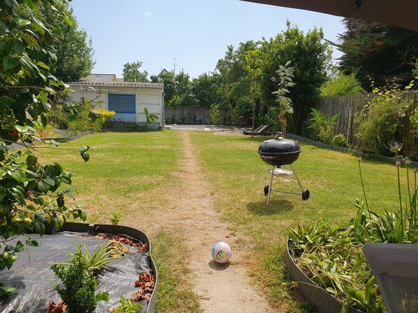 Un patio trasero con una parrilla, un sendero y un cobertizo pequeño.