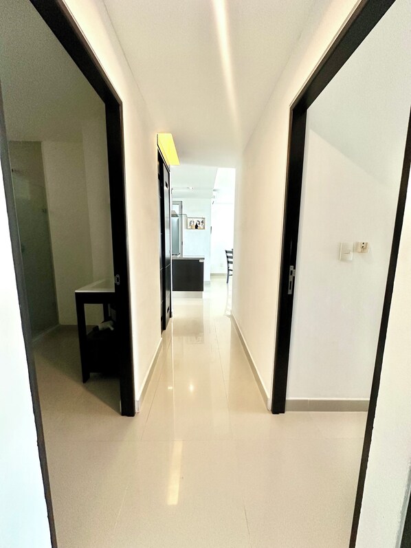 Un pasillo de diseño moderno, con suelo y paredes blancos y puertas de marco negro.