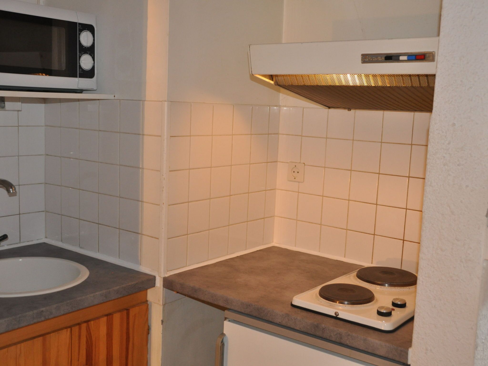 Een koelkast, een magnetron, kookgerei, borden en bestek