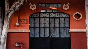 A building facade with a large black gate, a number '525' above it, and decorative elements on the wall. - Casa Márquez (Leon)