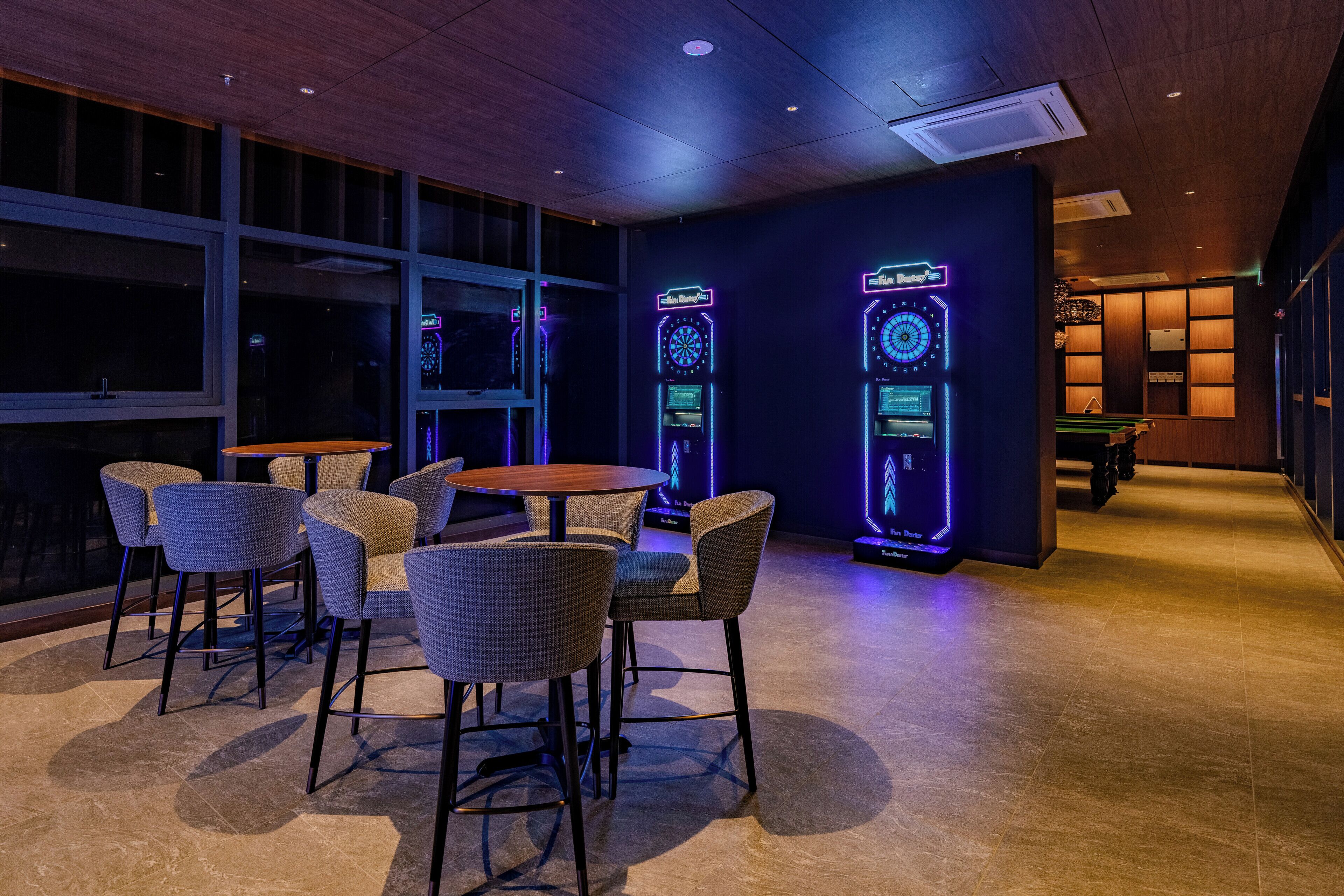 A bar area with bar stools, a pool table, and dartboards.