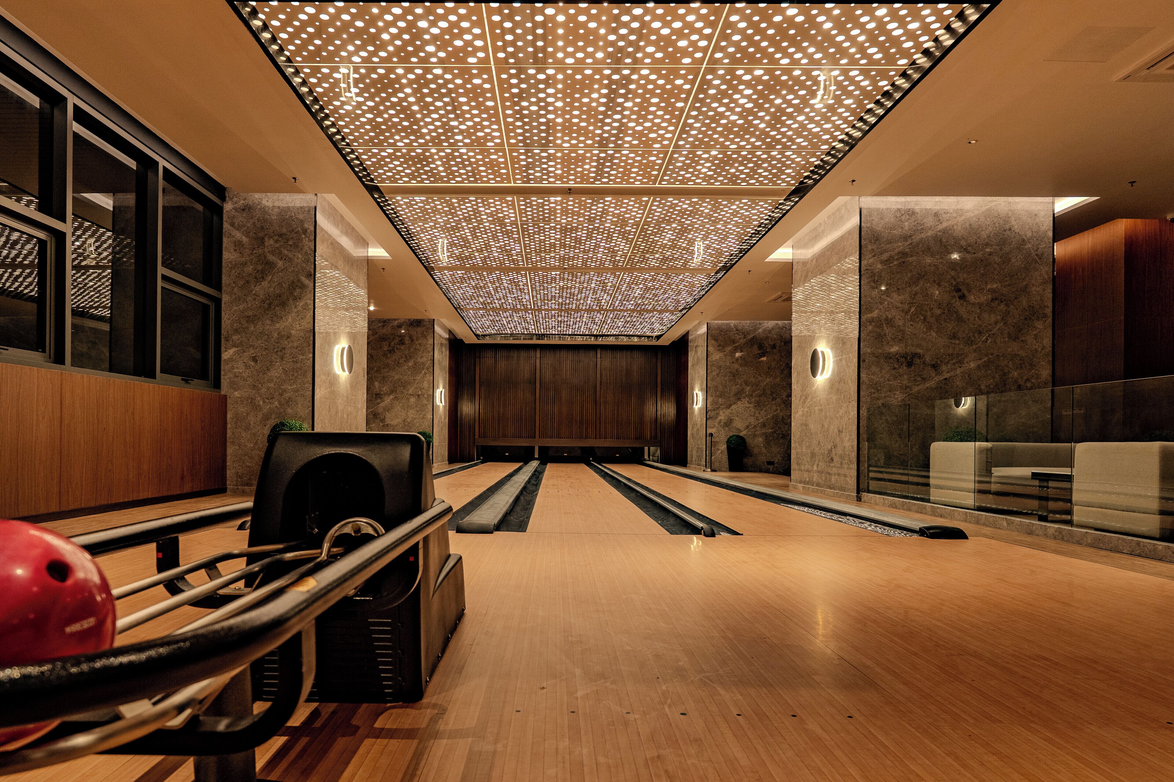 A bowling alley with a wooden floor, a bowling ball, and pins.