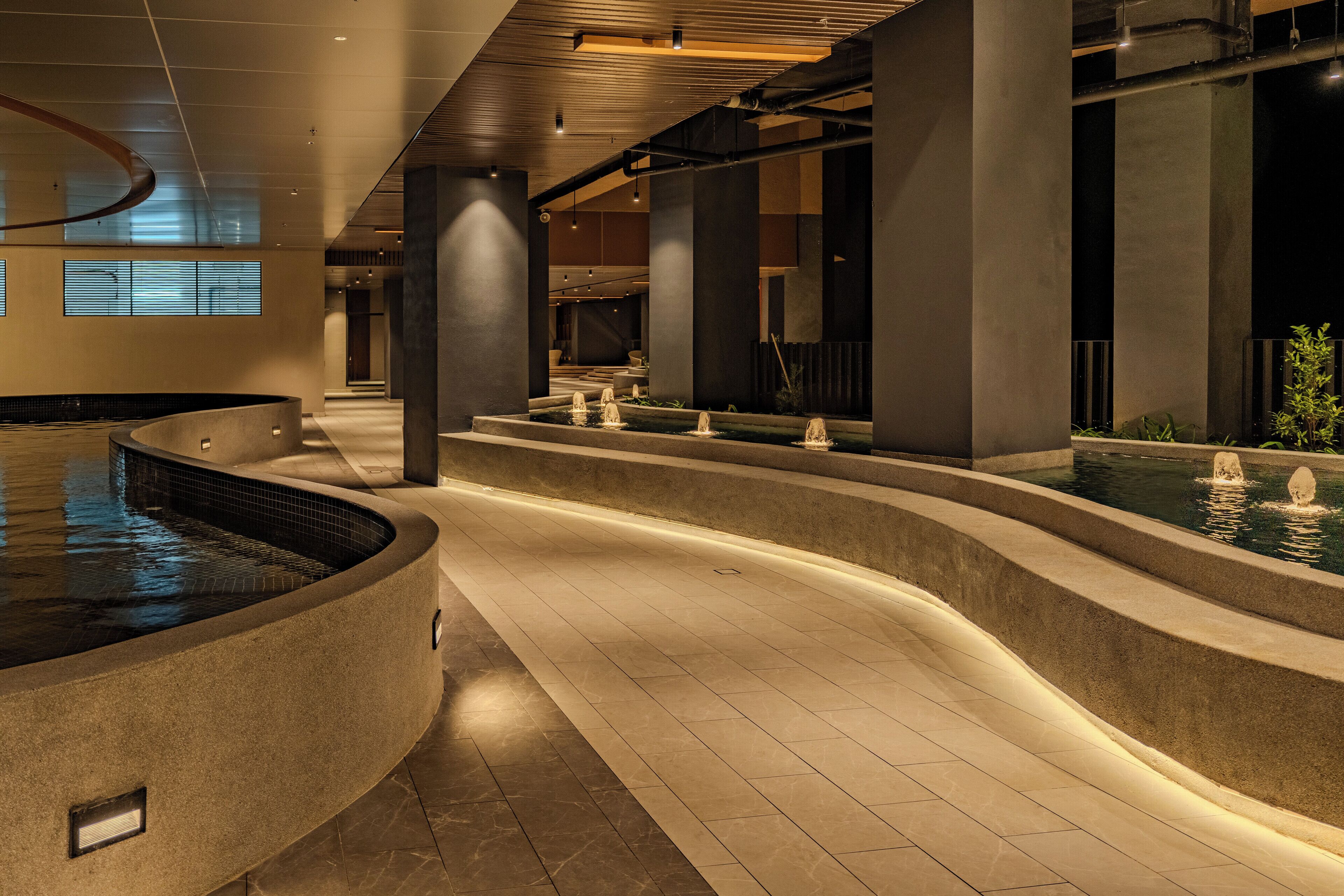 A modern indoor pool area with tiered water features and a curved design.