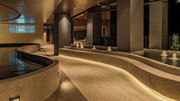 A modern indoor pool area with tiered water features and a curved design.