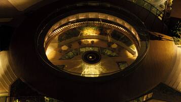 A circular atrium with a central fountain, glass railings, and a wooden floor.