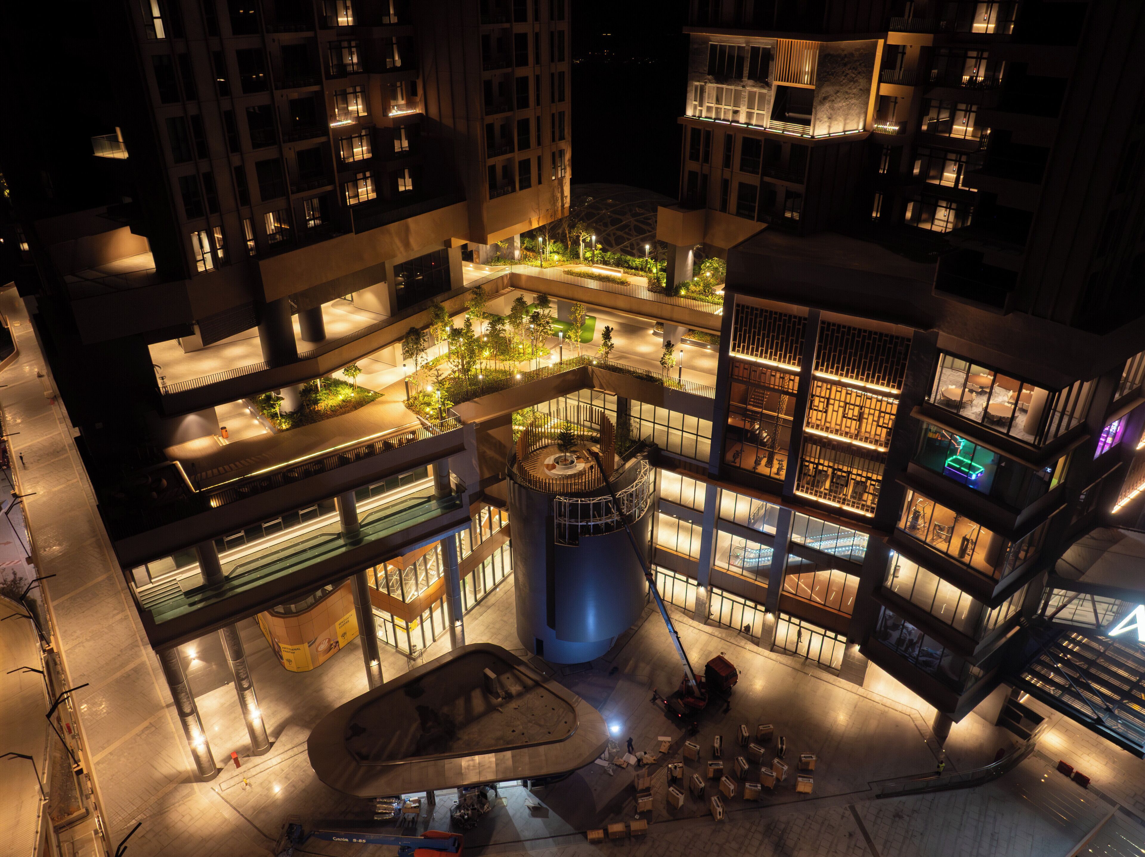 A multi-level urban building with interconnected balconies, a central atrium, and a parking area.