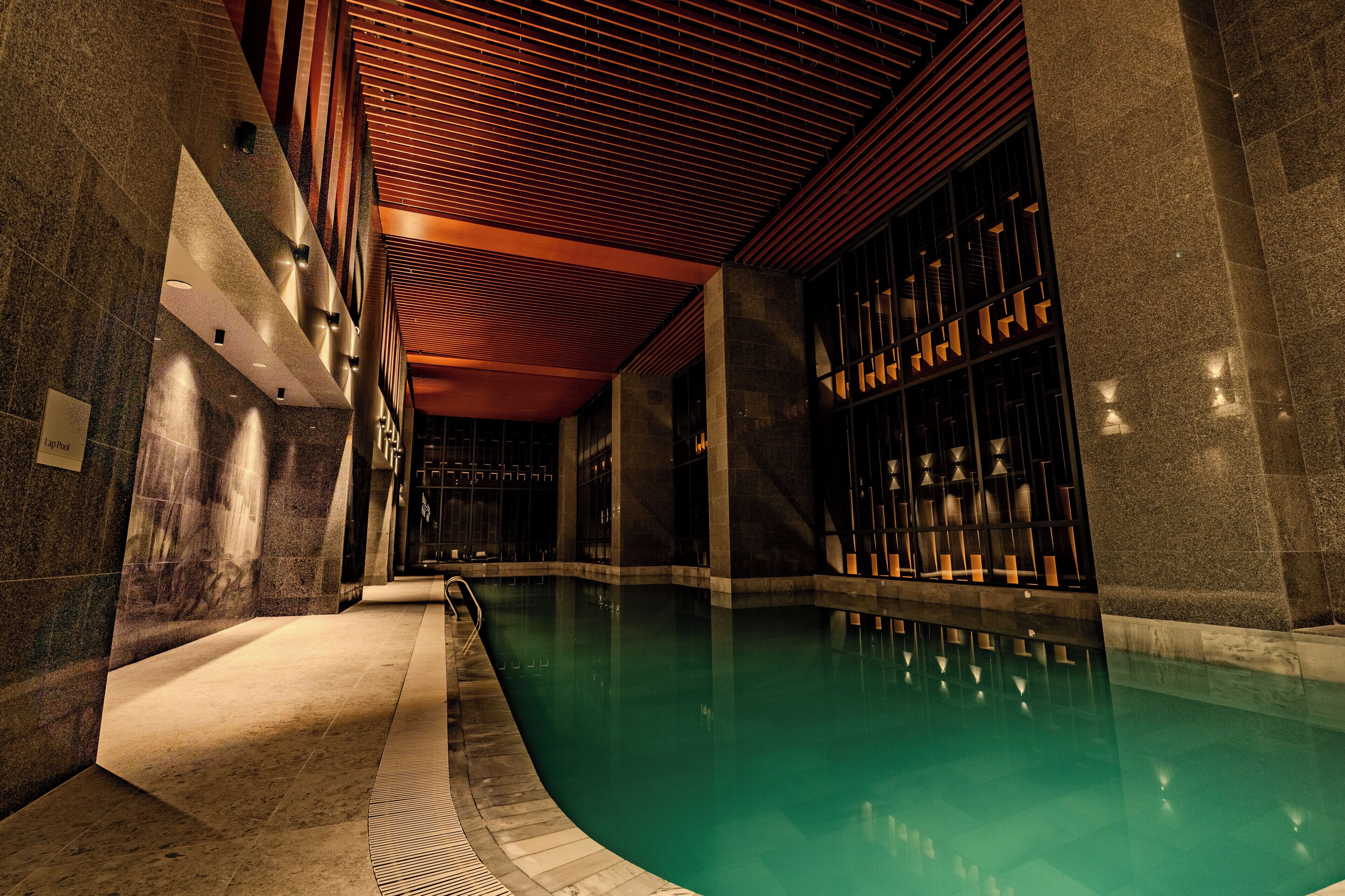 Una piscina con suelo de baldosas y techo de madera.